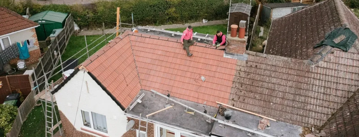 A tiled roof being replaced, with the new and existing roof side by side